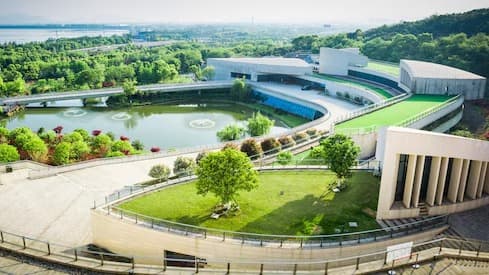 Aerial view of a modern architectural campus with landscaped gardens and a reflecting pool